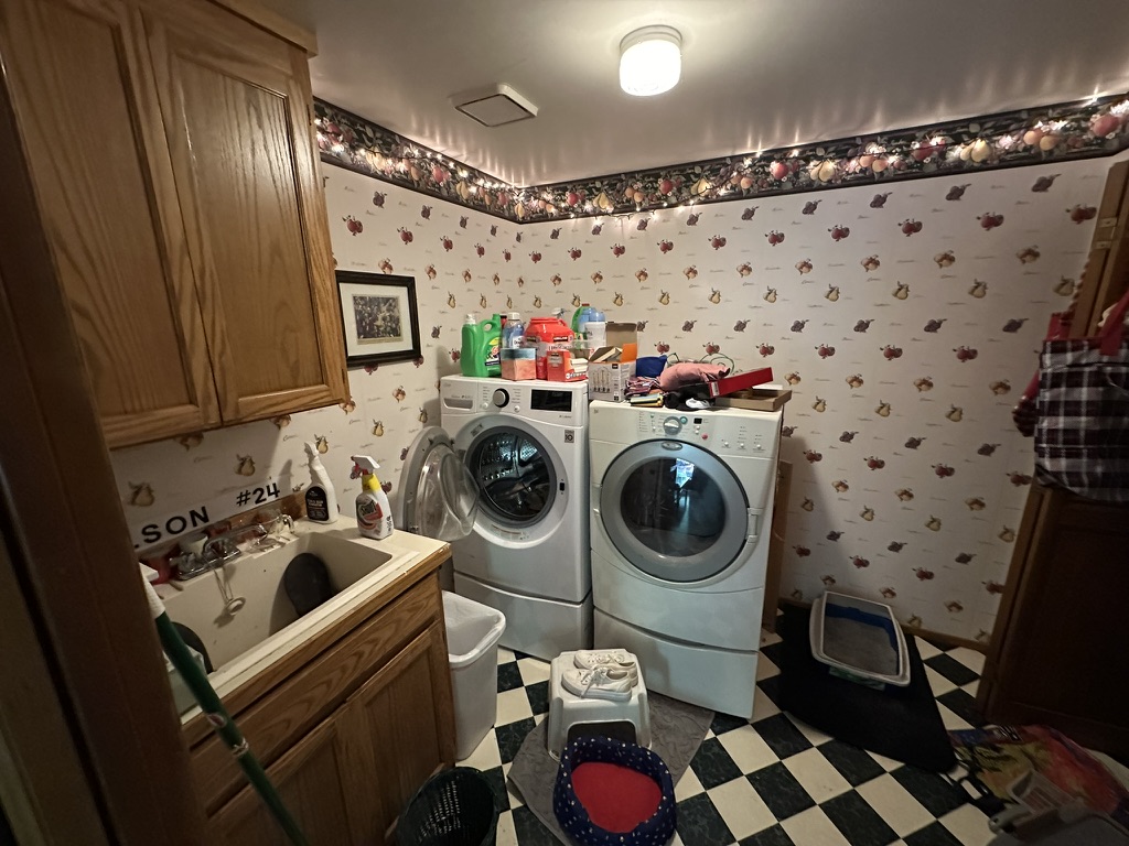 Before — side-by-side appliances, wood cabinetry, and patterned wallpaper
