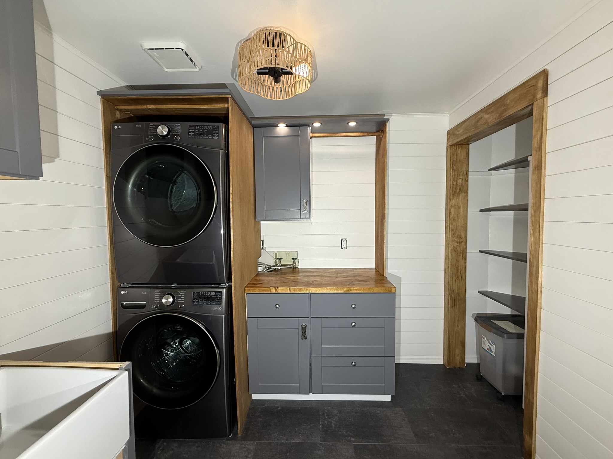 After — stacked appliances, painted cabinetry, and wood countertop