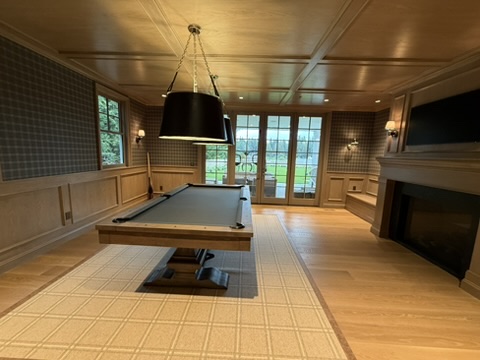 Billiard room with wood paneling, coffered ceiling, and fireplace