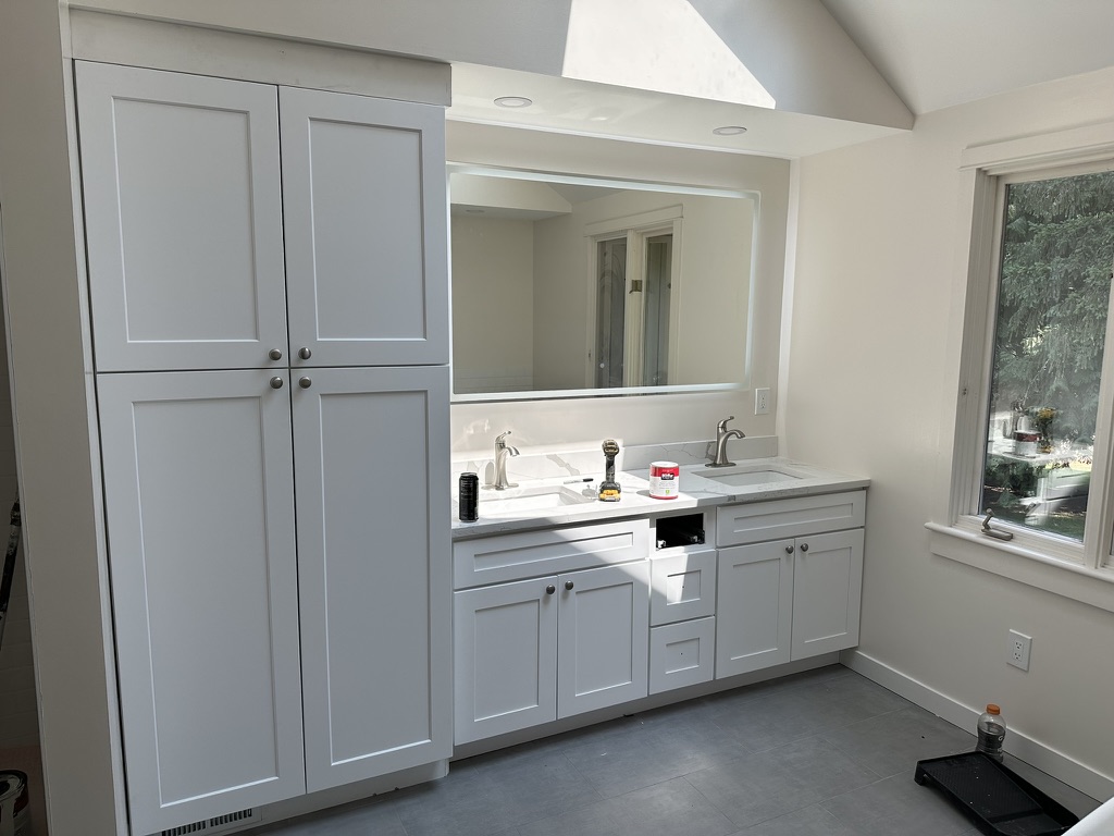 Updated double vanity, storage cabinetry, and illuminated mirror